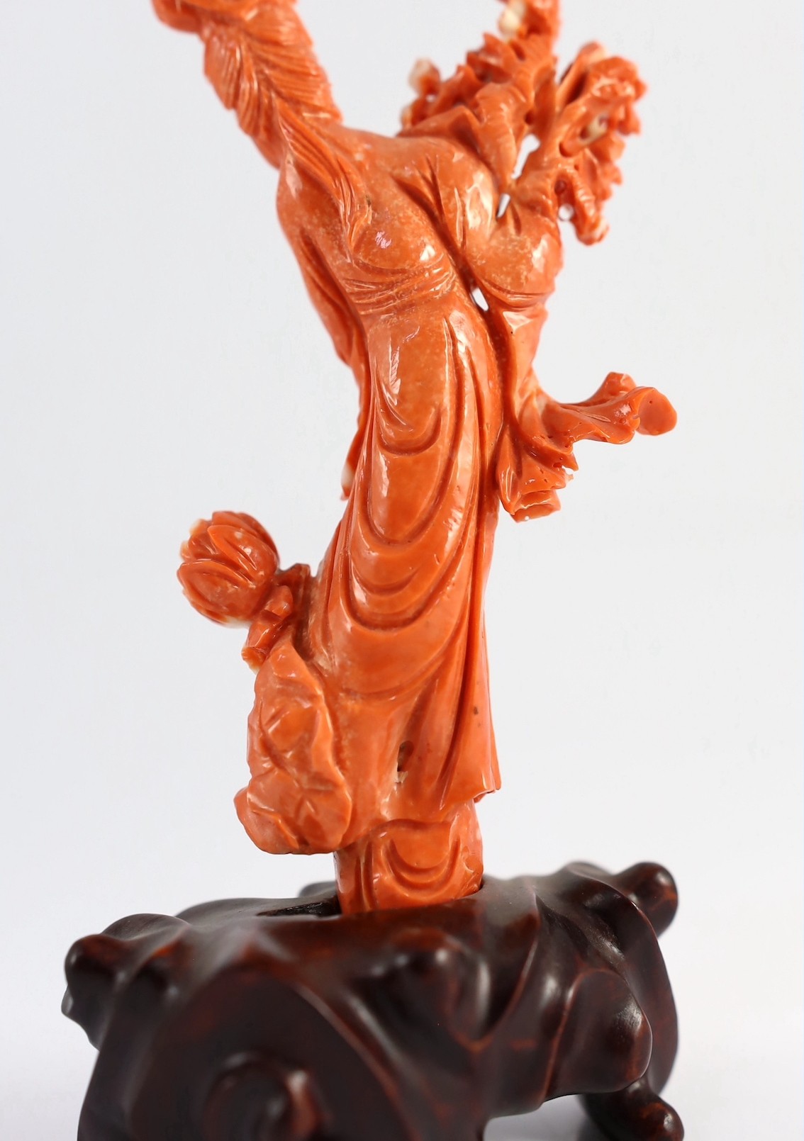 A Chinese carved coral figure of a flower fairy, 20th century, the carving 19cm high and 119g, wood stand